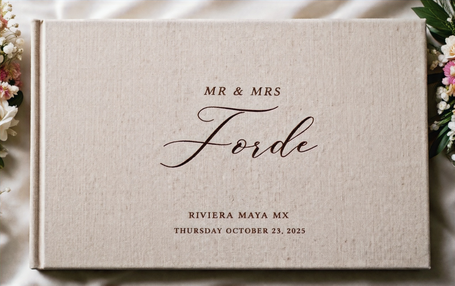 A linen wedding album embossed Mr and Mrs Forde, Riviera Maya MX, October 23 2025, with flowers.